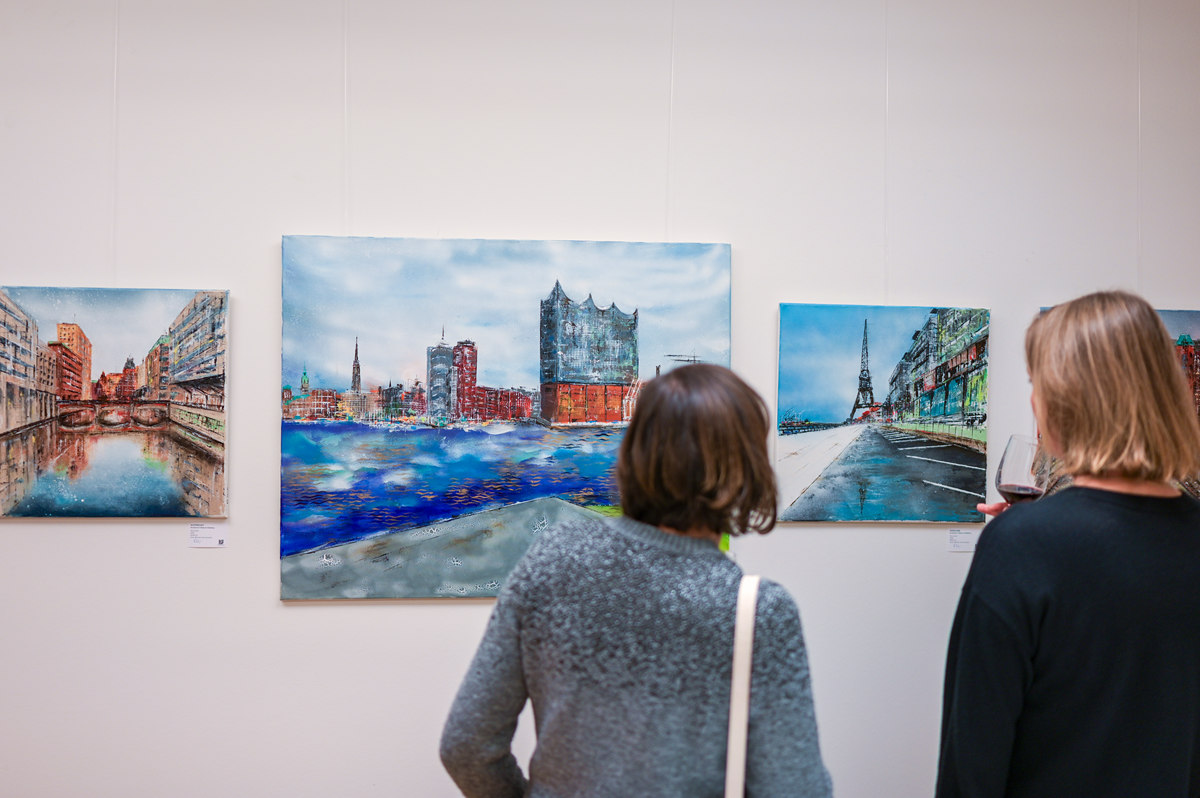 Gäste betrachten Gemälde bei einem Kunstevent im Rahmen einer Ausstellung von Nina Groth