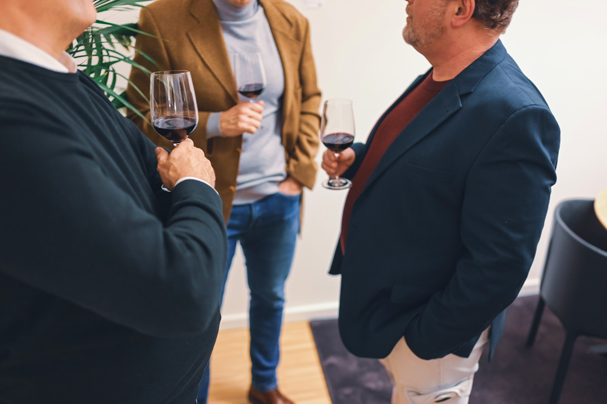 Teilnehmende im Gespräch bei einem Kunstevent mit Weinverkostung und Kunst