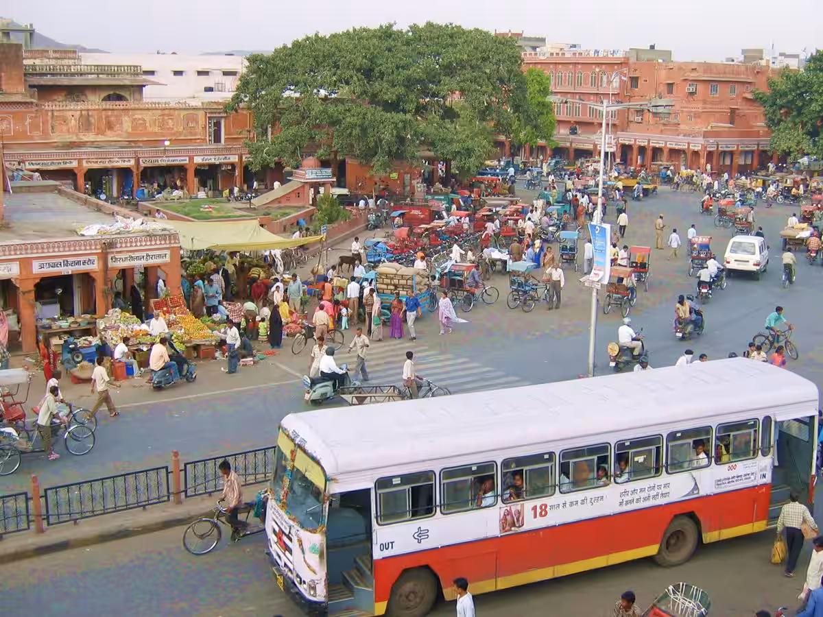 Straßenszene in Jaipur – Bewegung und Ordnung Belebte Straßenkreuzung in Jaipur mit Bussen, Fahrradrikschas, Motorrädern, Autos und Fußgängern