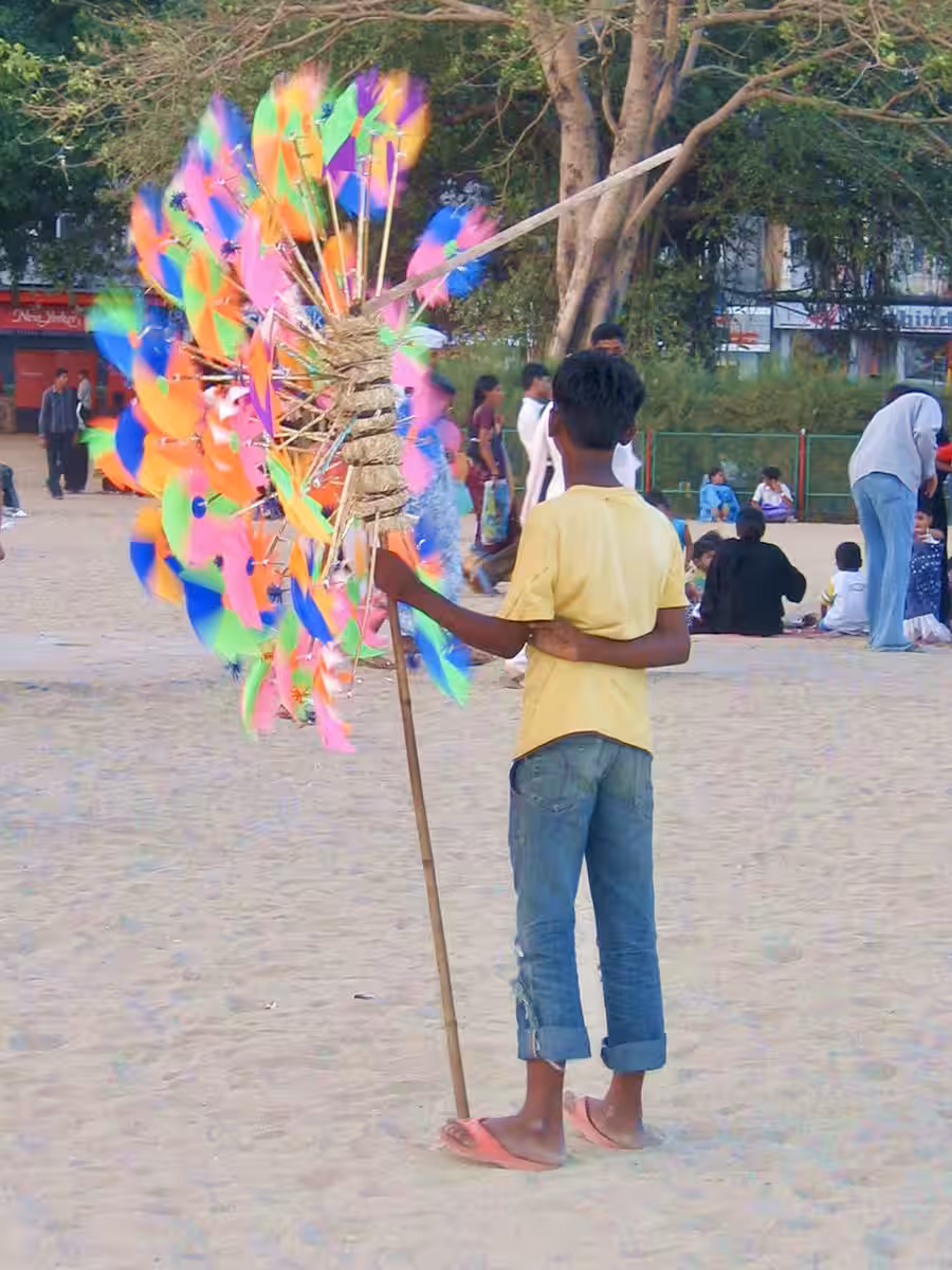Windradverkäufer in Indien – Inspiration für ein Stadtgemälde Windradverkäufer mit leuchtend bunten Windrädern in Mumbai