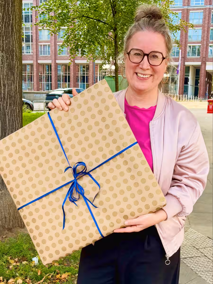 Kunst als Firmengeschenk – Nina Groth Künstlerin Nina Groth mit einem als Geschenk verpackten Originalgemälde.